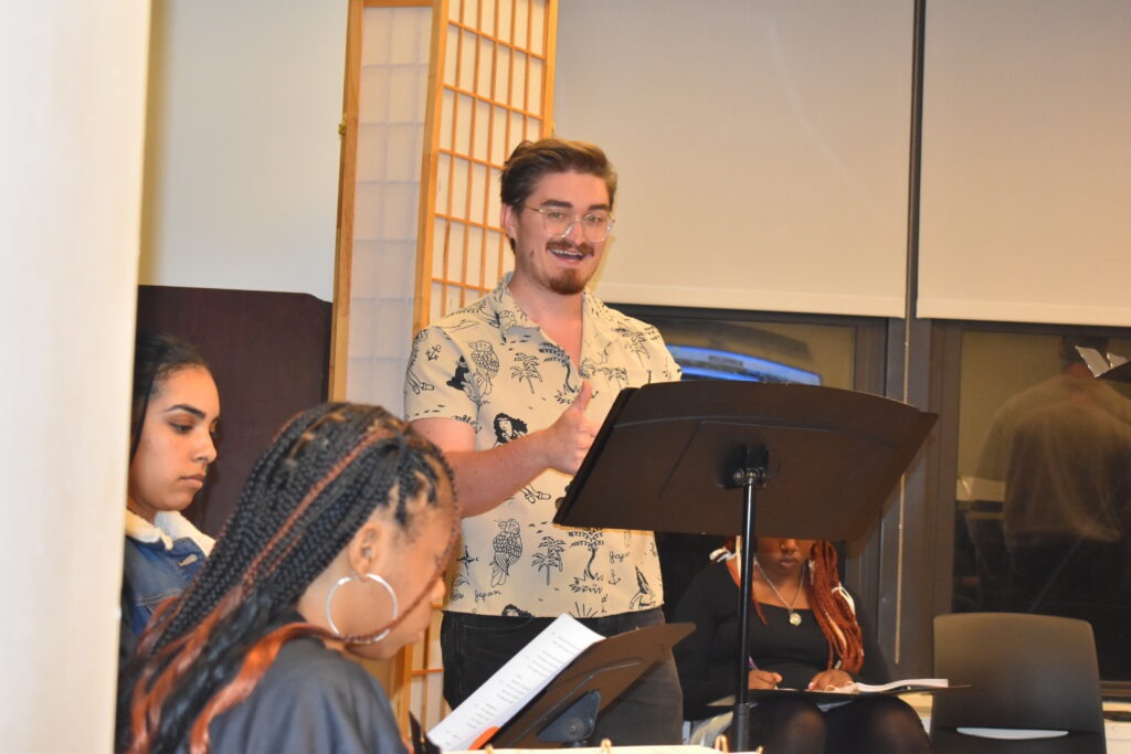 A male speaker in a patterned shirt gestures enthusiastically