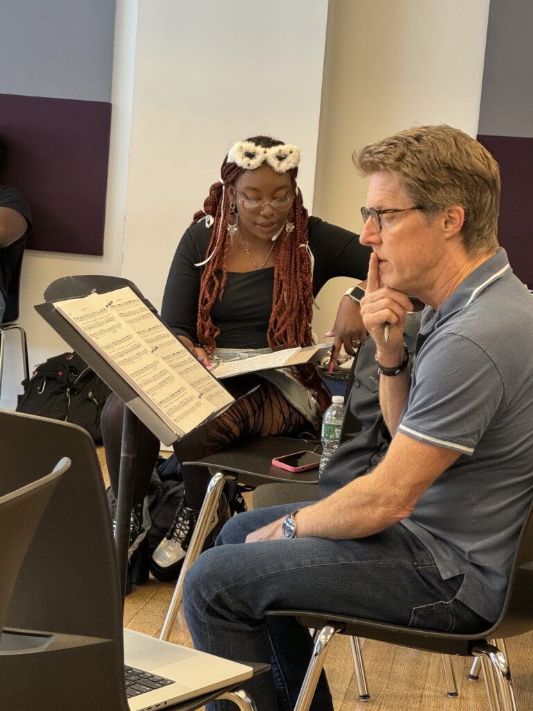 A focused young woman with long braids and studies sheet music